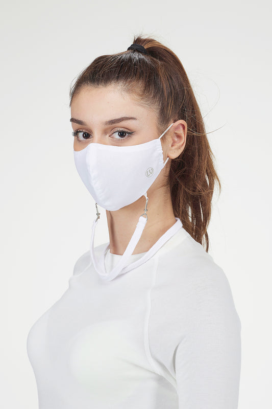 Woman wearing a white face mask against a plain background