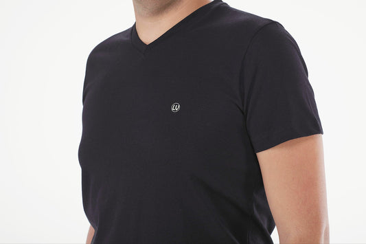 Man wearing a black t-shirt with a small logo on a white background