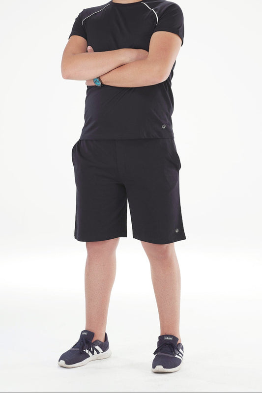 Man wearing a black athletic outfit with shorts on a white background