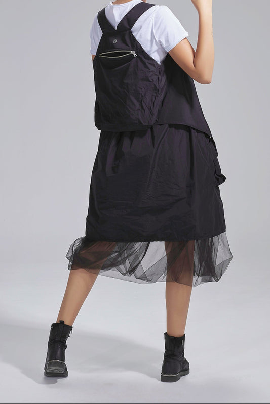 Woman wearing a black dress with a white shirt underneath on a gray background