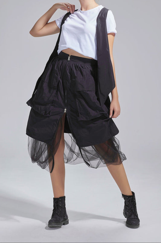 Woman wearing a black and white outfit with a sheer skirt on a gray background